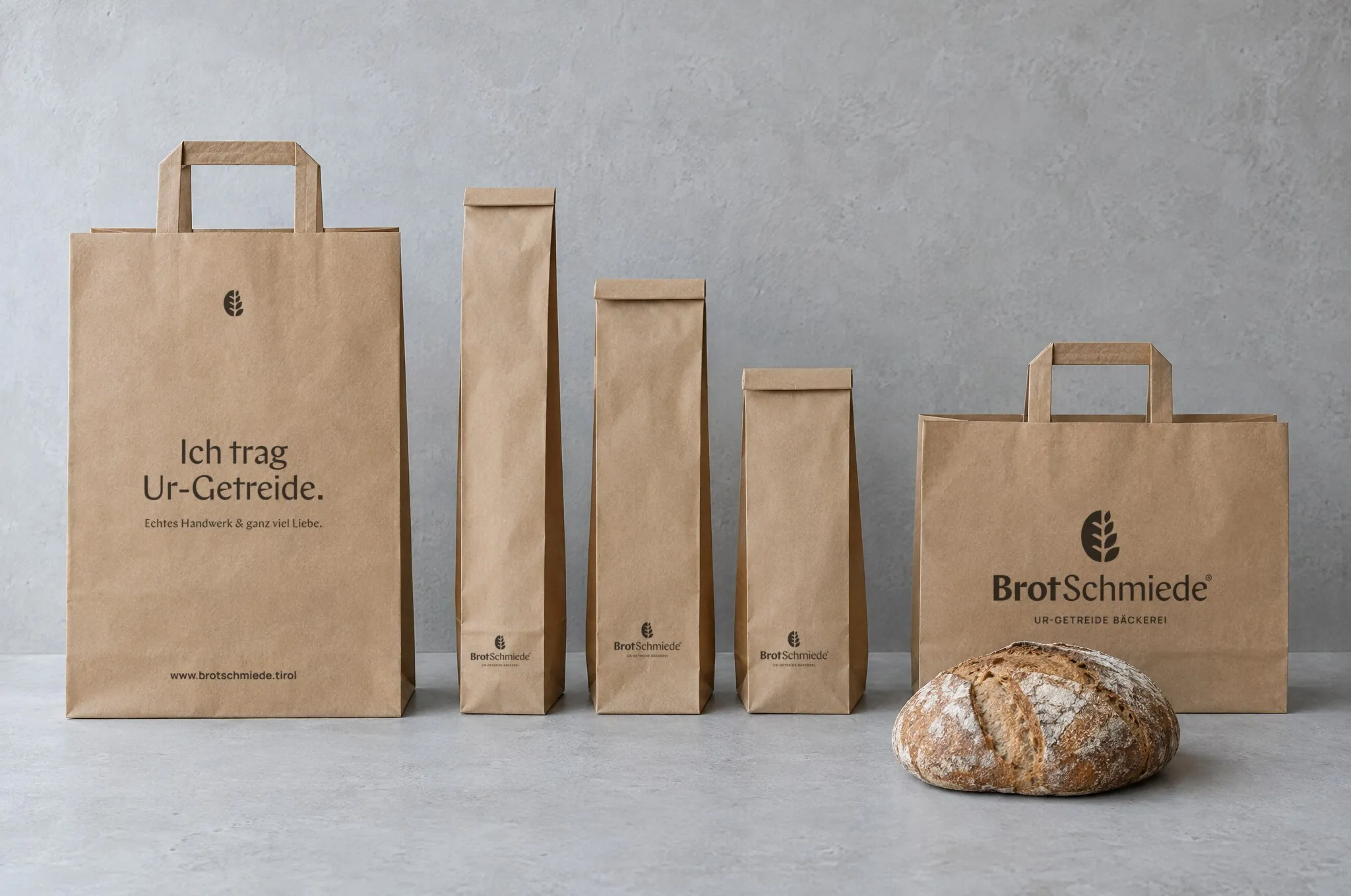 Kraftpapier-Tragetaschen und Brottüten mit BrotSchmiede-Logo auf einer Holztheke