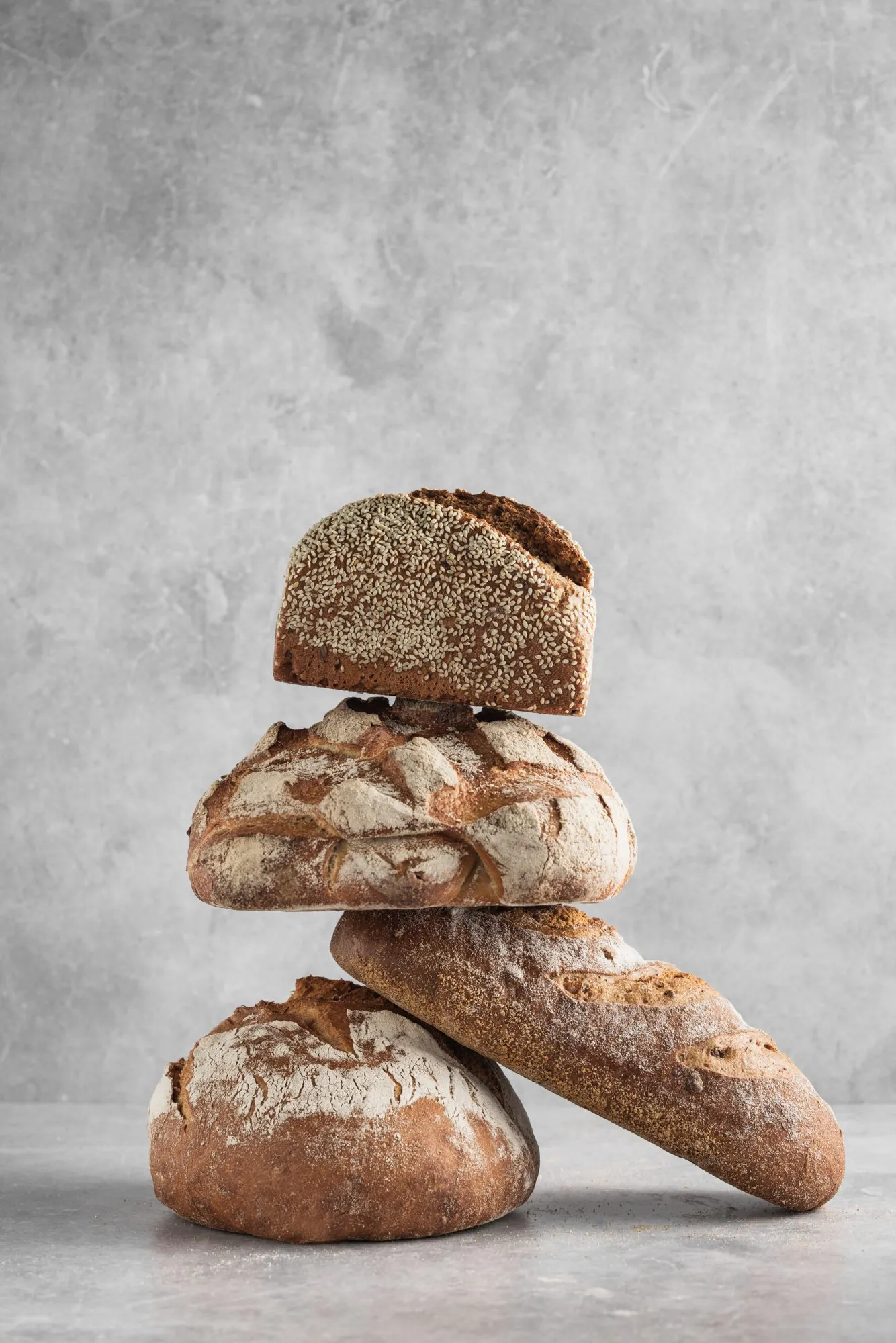 Gestapelte Ur-Getreide-Brote der Brotschmiede vor grauem Hintergrund