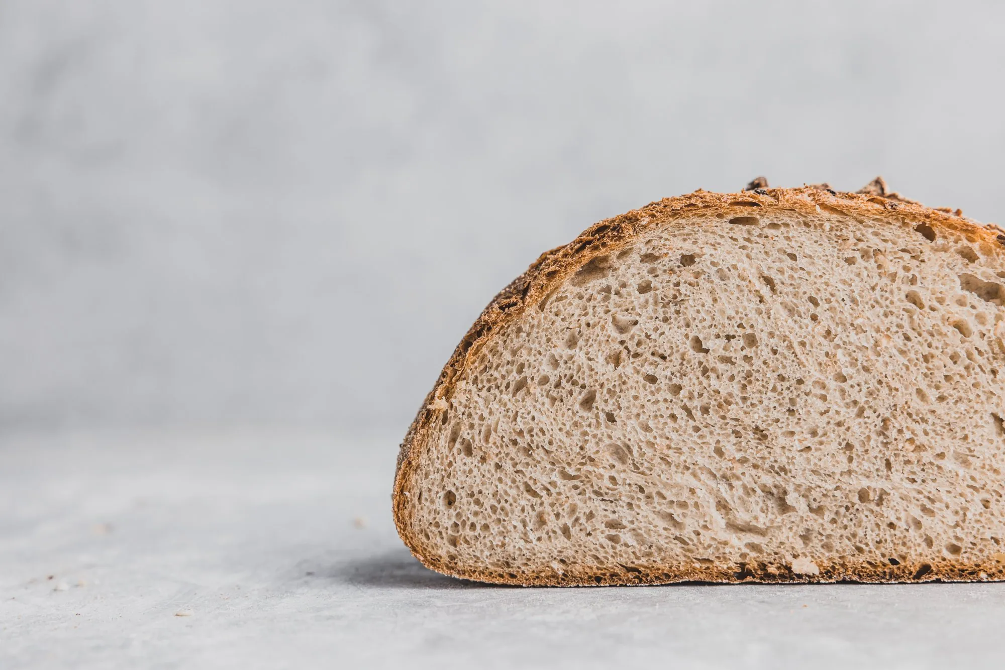 Angeschnittener Ur-Dinkel-Laib vor grauem Hintergrund