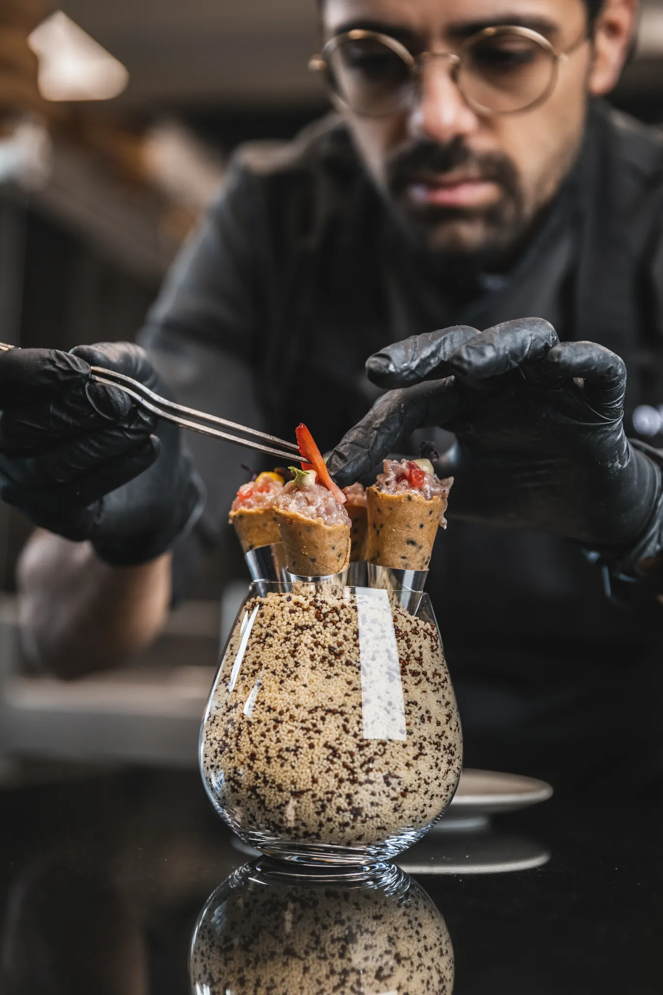 Koch richtet mit der Pinzette Häppchen im Glas an, Restaurant 23 Reasons