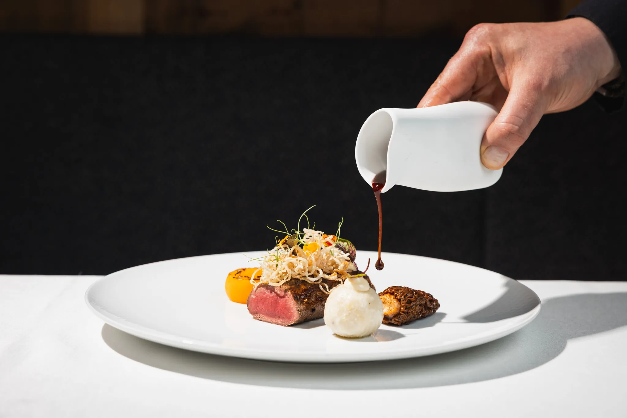 Jus wird aus einem Porzellankännchen über den Hauptgang gegossen