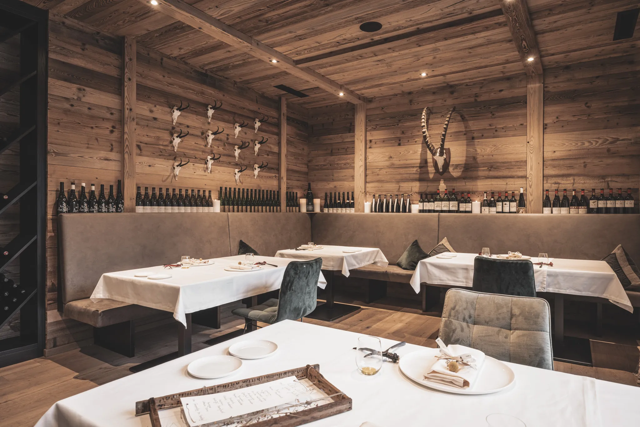 Eingedeckte Tische in der Jagdstube vor der Weinwand