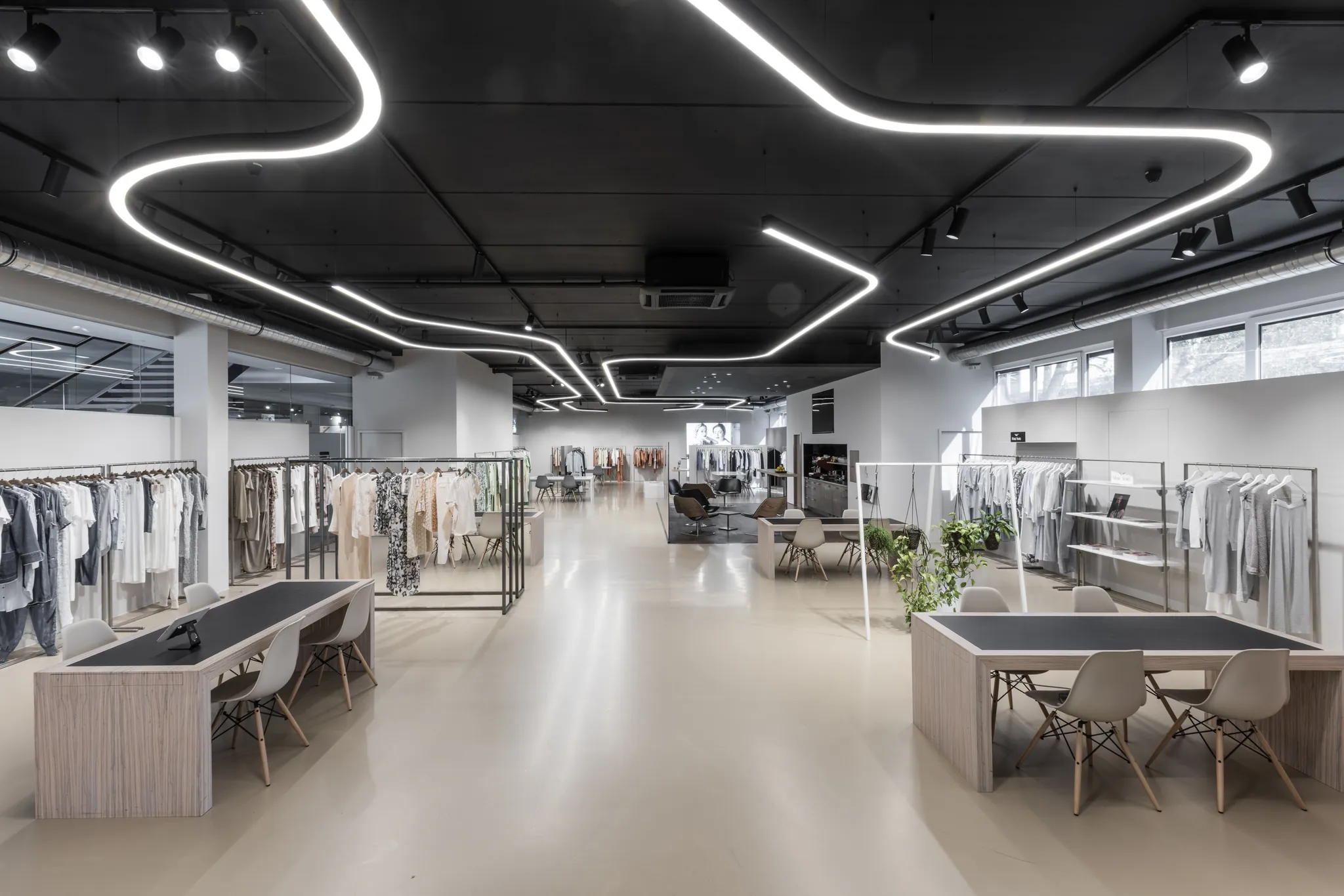 Showroom der Modeagentur KLAUS mit geschwungener LED-Deckenbeleuchtung und Kollektionen