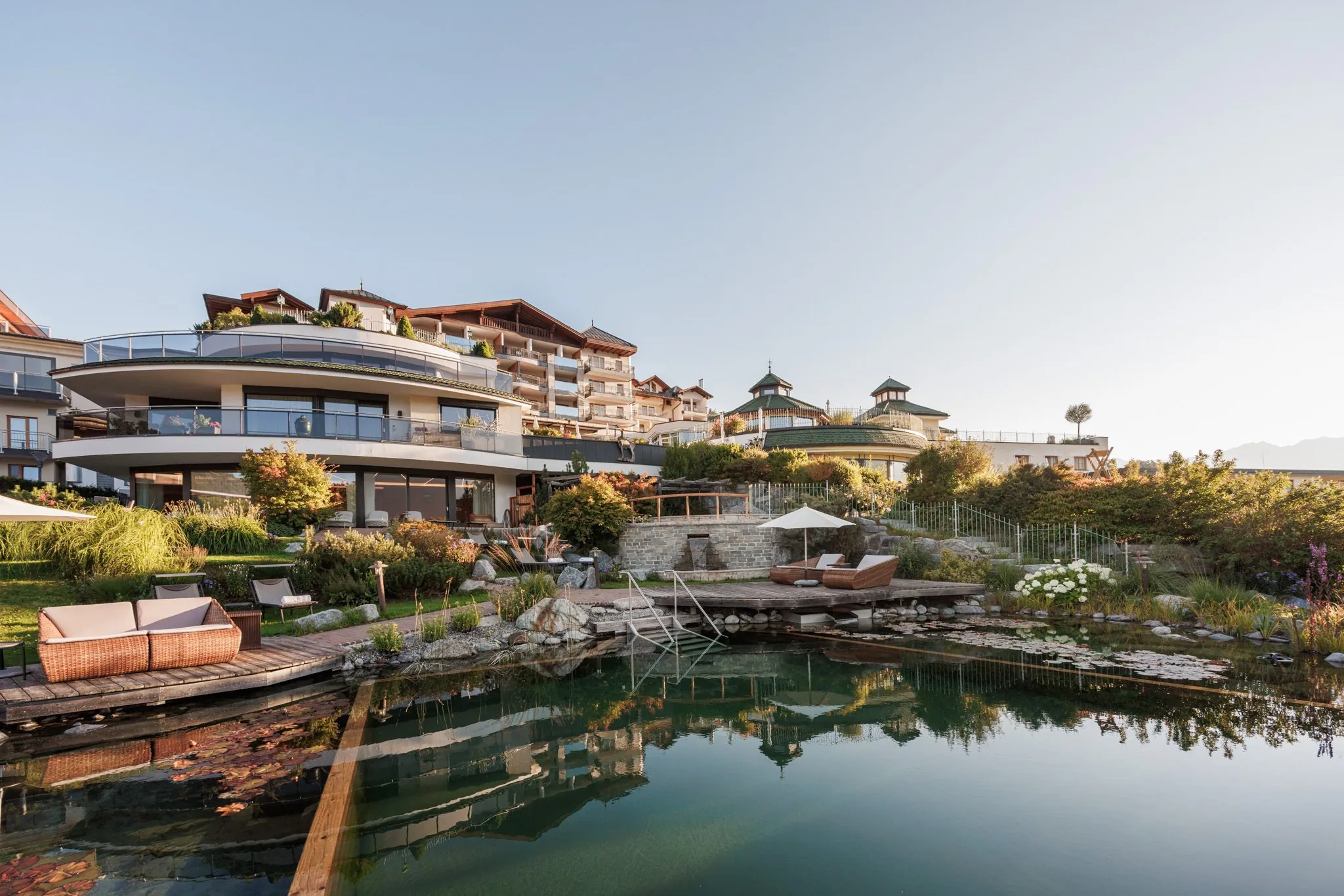 Naturteich der Wellnessresidenz Schalber im Abendlicht mit Hotel im Hintergrund