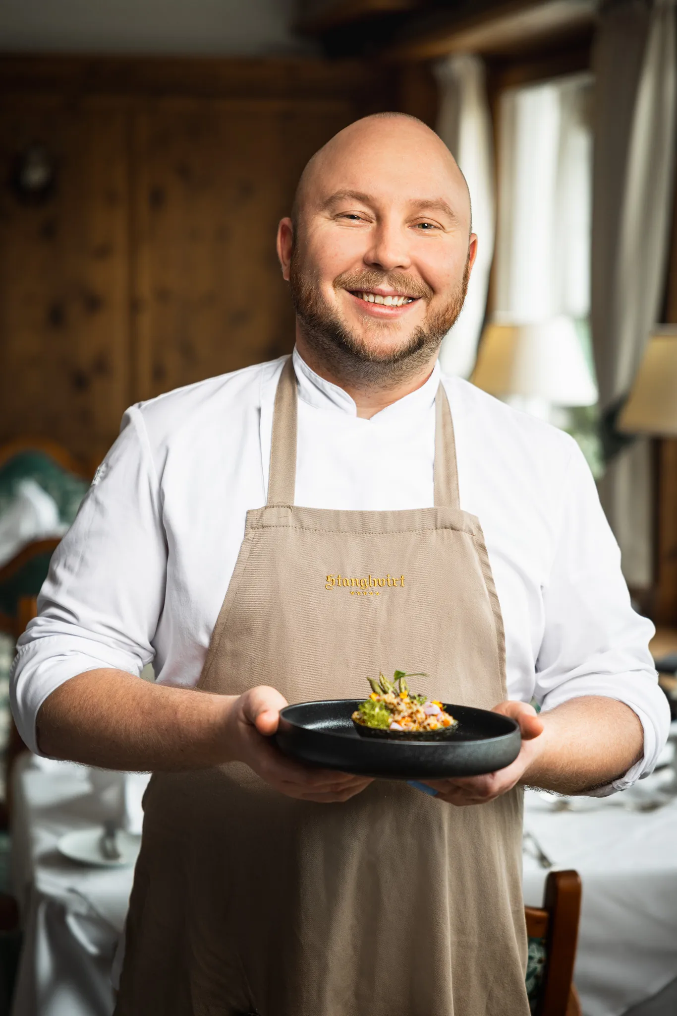 Lachender Küchenchef präsentiert ein Gericht, Stanglwirt