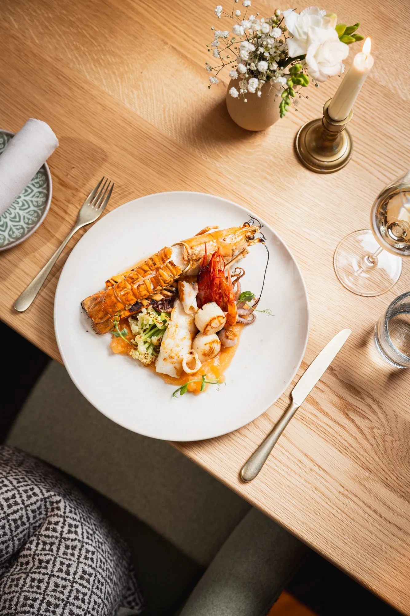 Meeresfrüchteteller auf Holztisch mit Blumen und Kerze, Stanglwirt